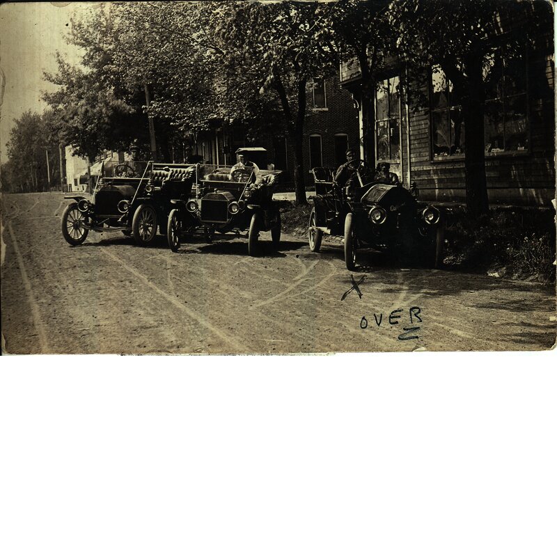  Postcard view of three early (1910s) automobiles, one a Ford and one an Oakland. The postcard was sent on June 12, 1911 from Mort(?) Powers of New Sharon, Iowa, to John Mincer of Grinnell, Iowa. The X under the automobile on the right probably identifies Mr. Powers. Photo was possibly taken in New Sharon. Drake Community Library (Grinnell, Iowa) Archives. McNally photographs. Collection #1, Series #1-1.