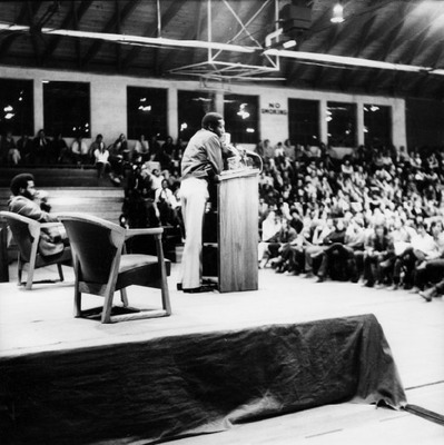 Dick Gregory speaking at the Black Martyr's Weekend, 1971. The 1971 Black Martyr's Weekend featured a full schedule including a “Soul Food Bazaar”, film screenings of “The Olive Tree of Justice” and “Viridiana”, a concert by The Impressions, Poetry and dramatic readings by actress Val Gray Ward, a lecture by Black nationalist Christian minister The Rev. Albert B. Cleage, Jr.,  a performance of "The Lion Writes” by the Cleveland theater group The Karamu Players, a performance by CBS, and a lecture with activist and comedian Dick Gregory.  Gregory ended his lecture with the quote:”You have the all-important job of returning sanity to an insane society … The . . . thing you young folks have that scares us old folks is your moral force.” (S&B April 9, 1971 pg 3).  Cleage focused his lecture on the stages of revolution, stating that “First, you cry out. Then you hit at the nearest point of irritation”(S&B April 9, 1971 pg 3). 