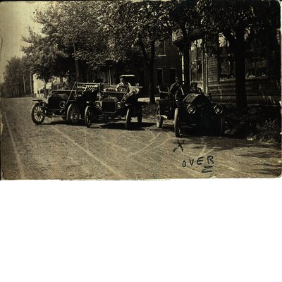  Postcard view of three early (1910s) automobiles, one a Ford and one an Oakland. The postcard was sent on June 12, 1911 from Mort(?) Powers of New Sharon, Iowa, to John Mincer of Grinnell, Iowa. The X under the automobile on the right probably identifies Mr. Powers. Photo was possibly taken in New Sharon. Drake Community Library (Grinnell, Iowa) Archives. McNally photographs. Collection #1, Series #1-1.